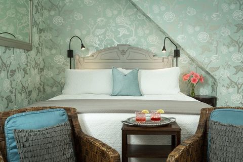 Bedroom interior with teal wallpaper, two chairs and cocktails