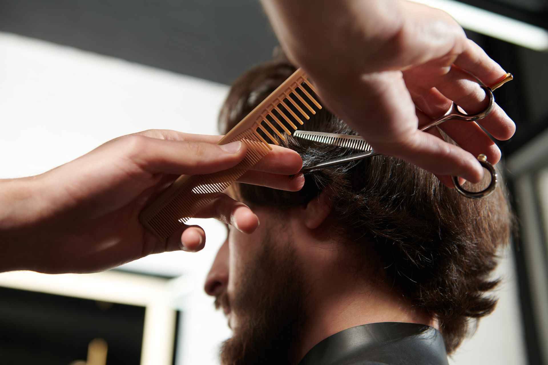 Barber giving a man a haircut with clippers and comb