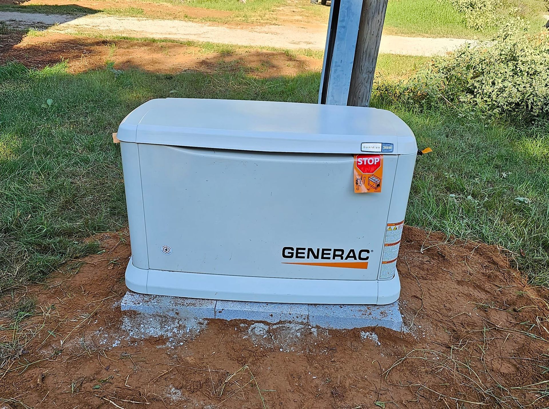 A generator is sitting on top of a pile of dirt in the grass.