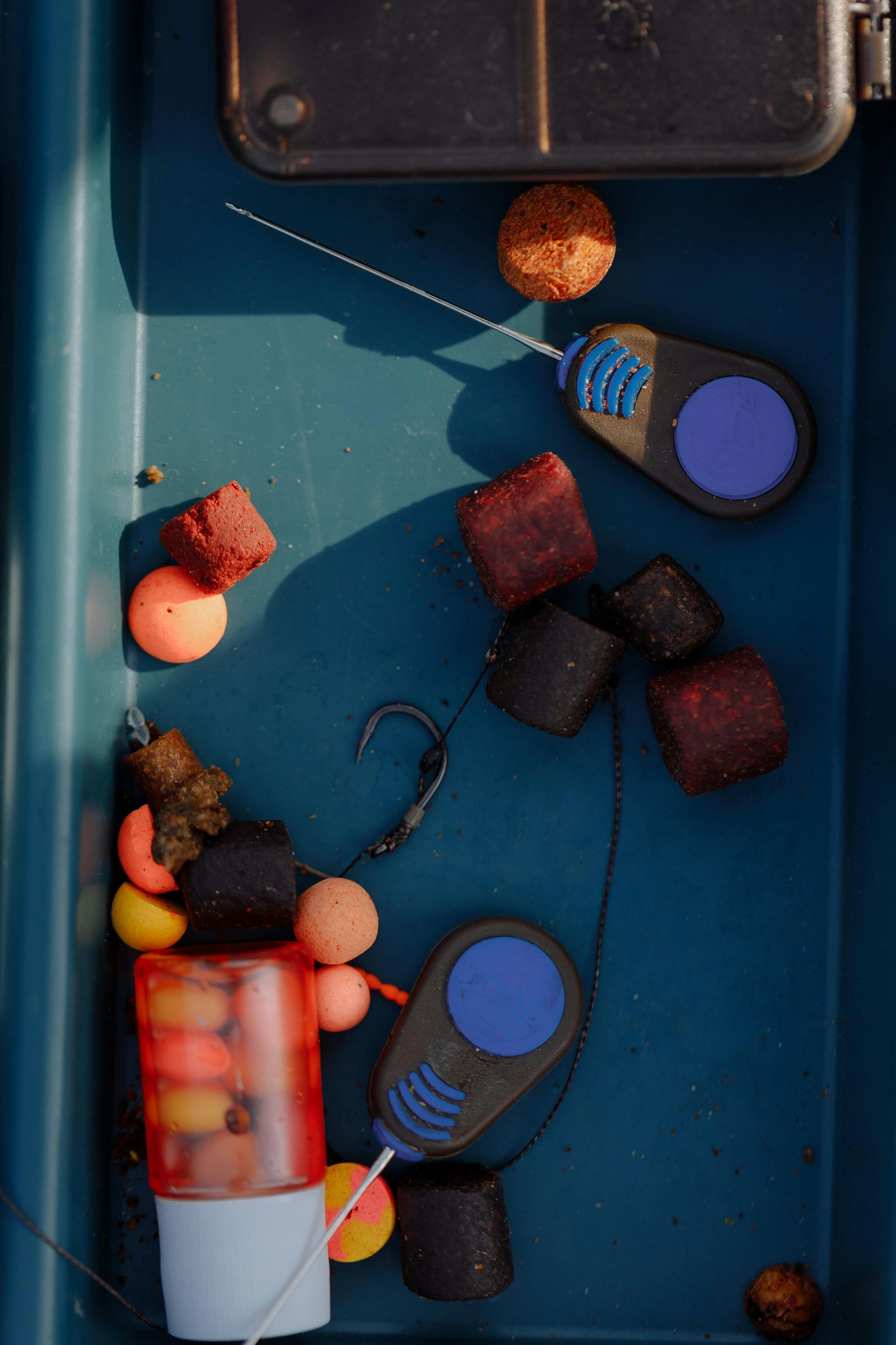 Fishing tackle box with bait, hooks, and tools. Blue and orange colors.