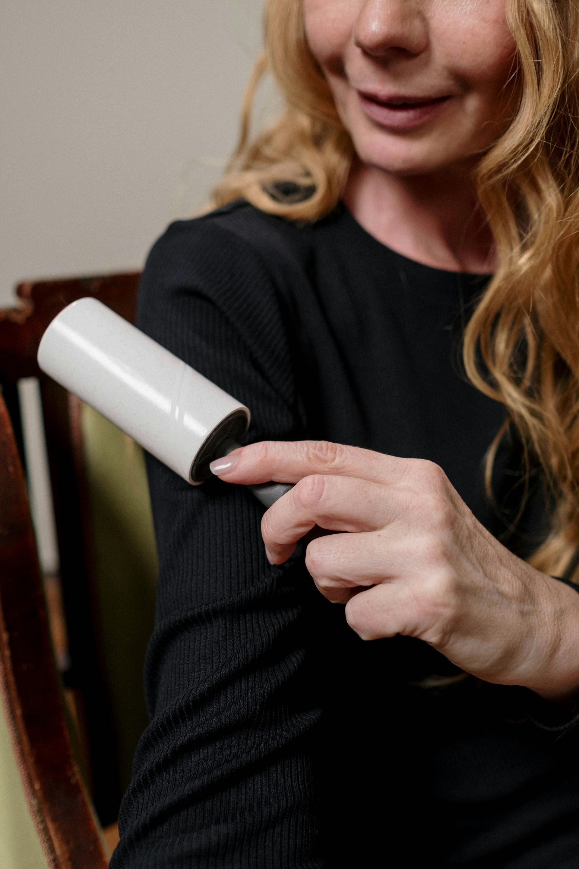Woman uses lint roller on black sleeve.