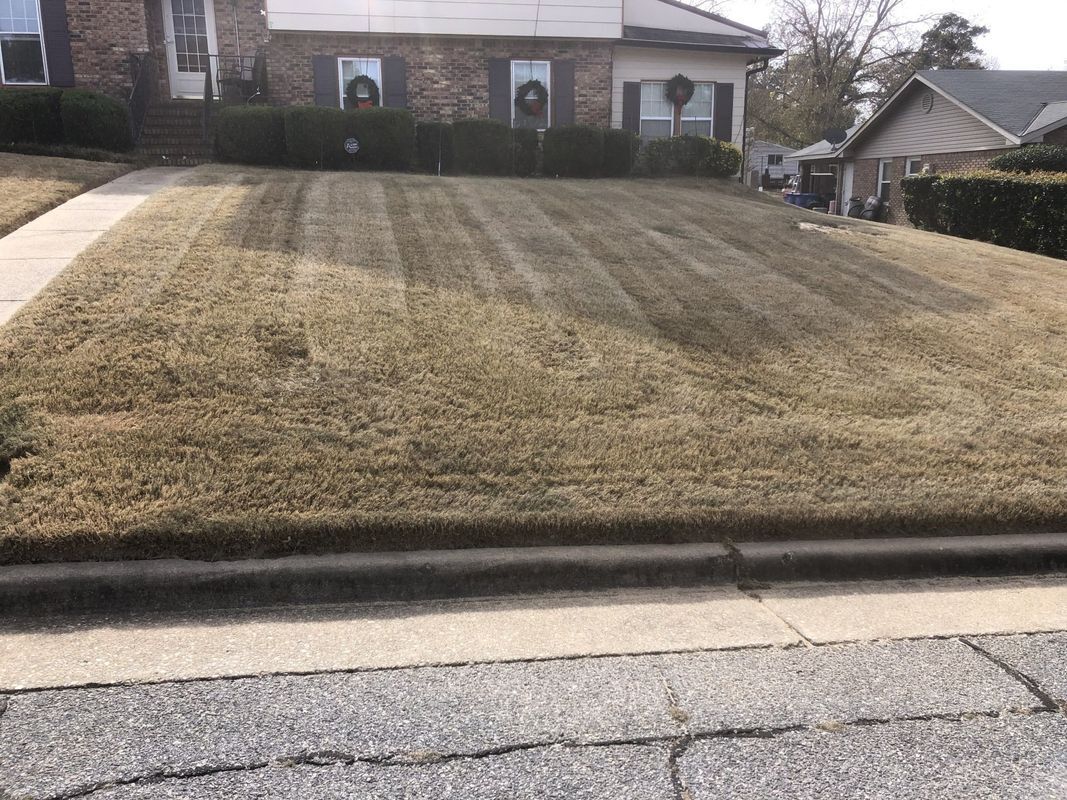A lawn is being mowed in front of a house.