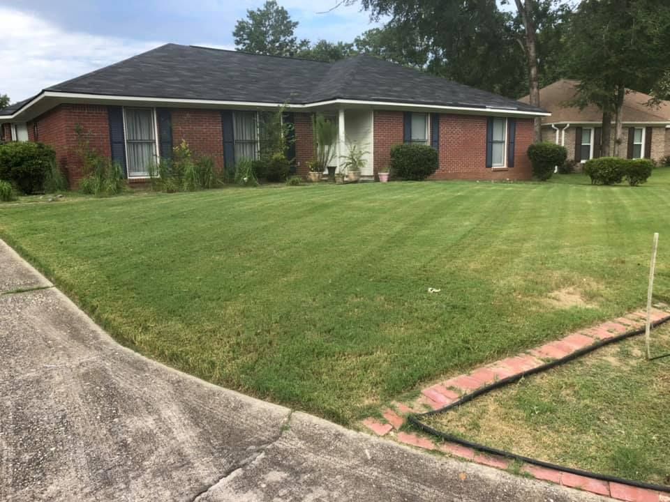 A brick house with a lush green lawn in front of it.