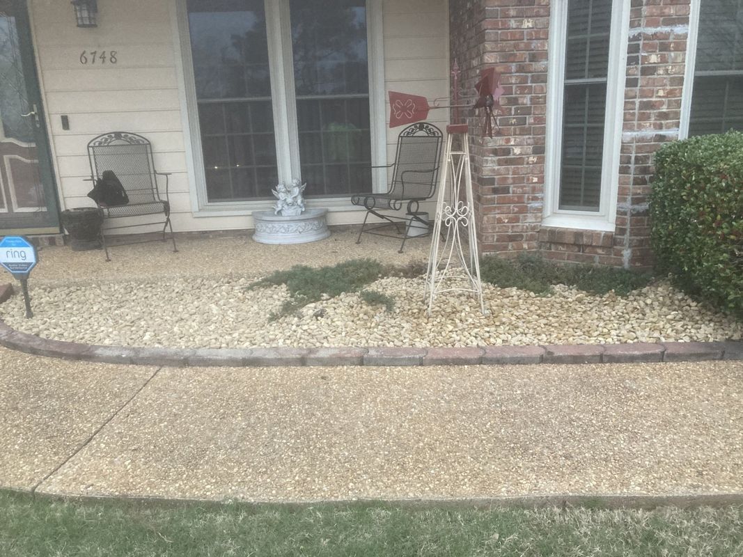 A brick house with a concrete walkway in front of it.