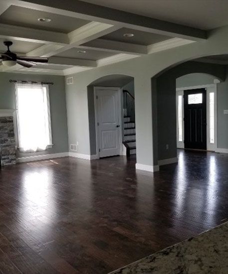 Spacious living room with dark wood floors, sage walls, and a decorative ceiling.