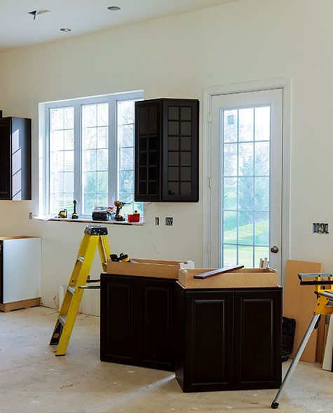 Kitchen remodel in progress; cabinets, ladder, tools, and window.