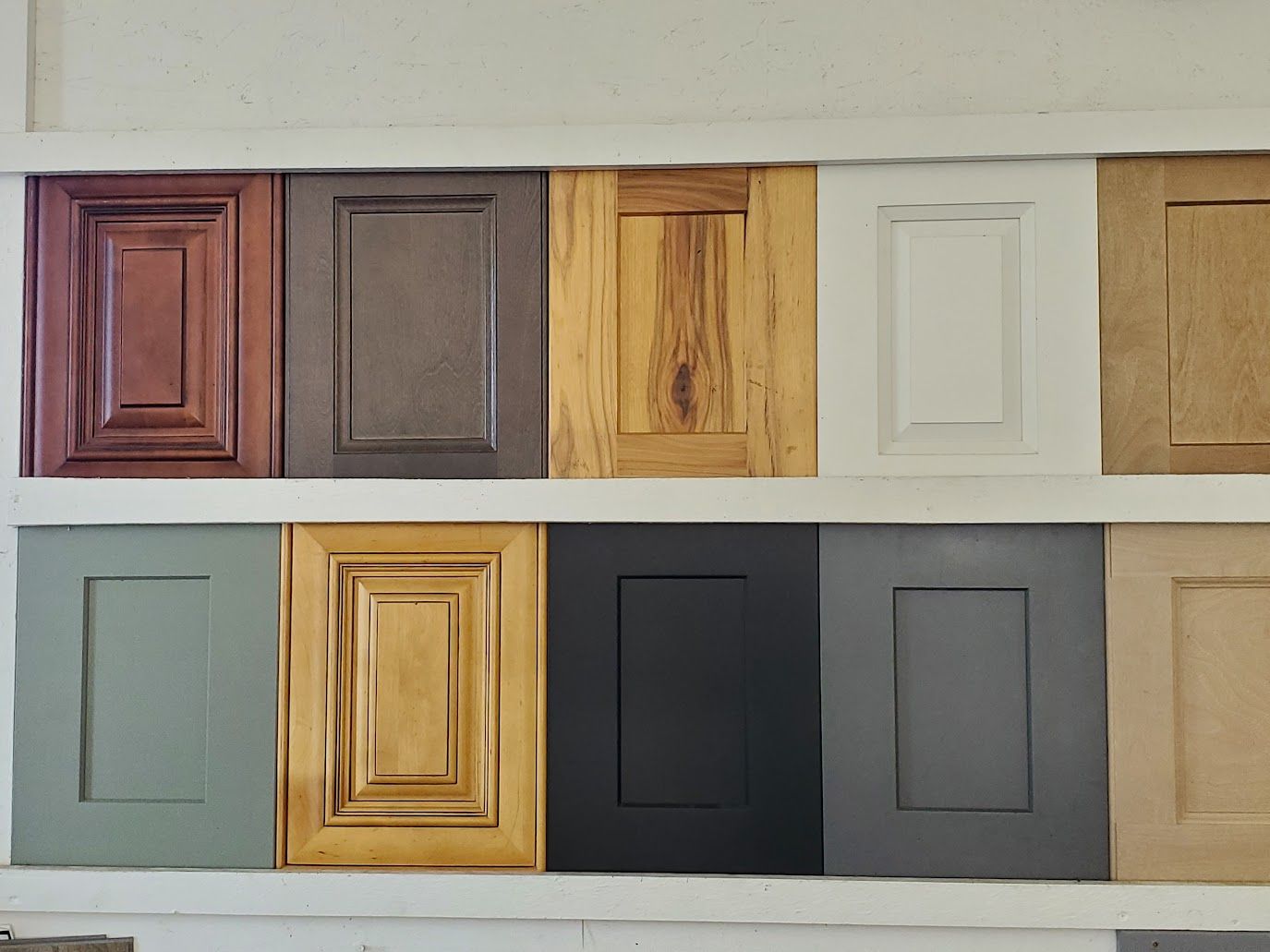 Cabinet door samples in various colors and finishes displayed on a shelf.
