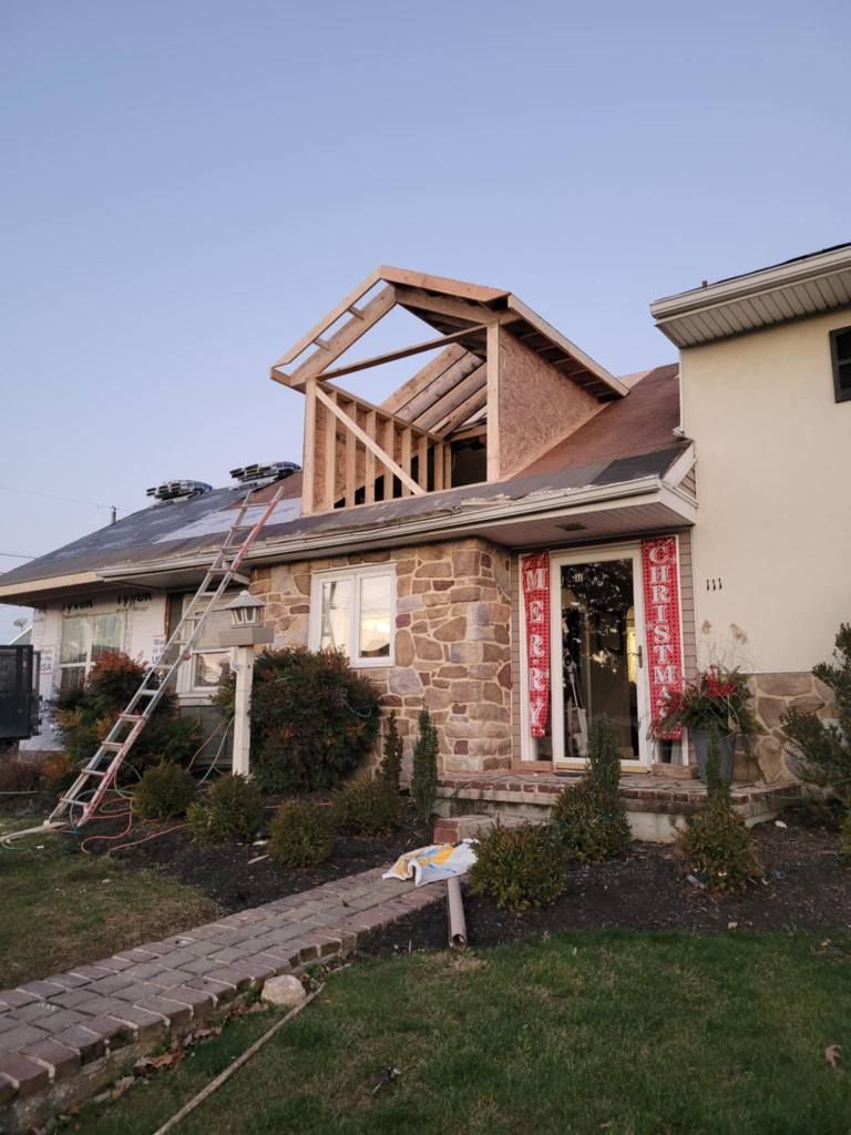 House under construction; roof partially open, framing visible; ladder leaning against the roof.