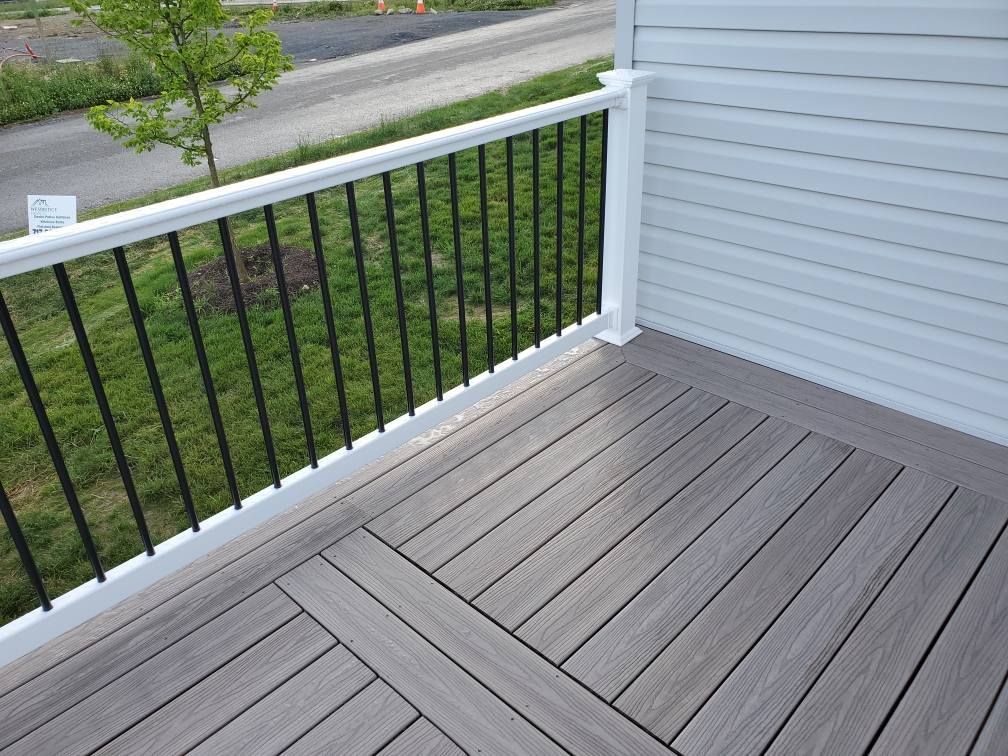 Deck with gray composite boards, black railing, and white trim next to white siding.
