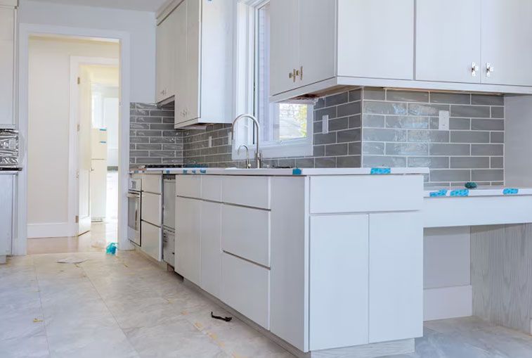 White kitchen with gray backsplash and cabinets; under construction.
