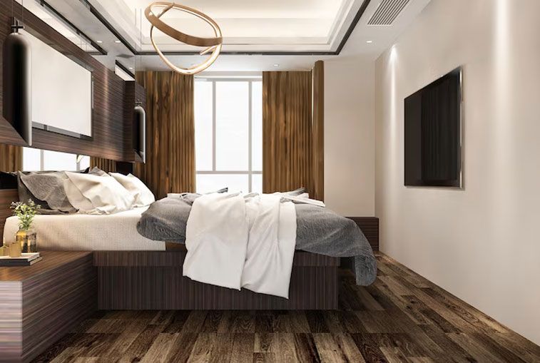 Modern bedroom with a bed, TV, window, wood flooring, and a circular light fixture.