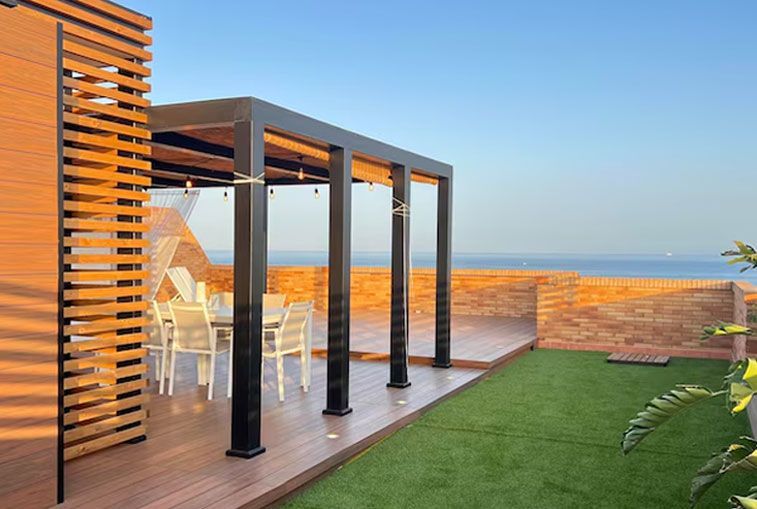 Rooftop patio with black pergola, dining set, artificial grass, and ocean view.