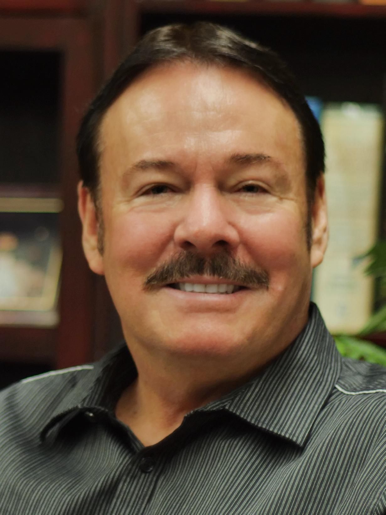 A man with a mustache is smiling for the camera