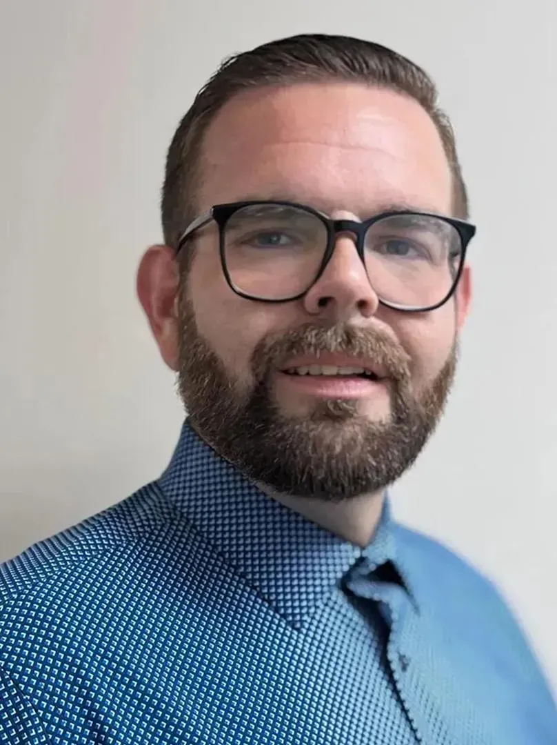 A man with a beard and glasses is posing for the camera