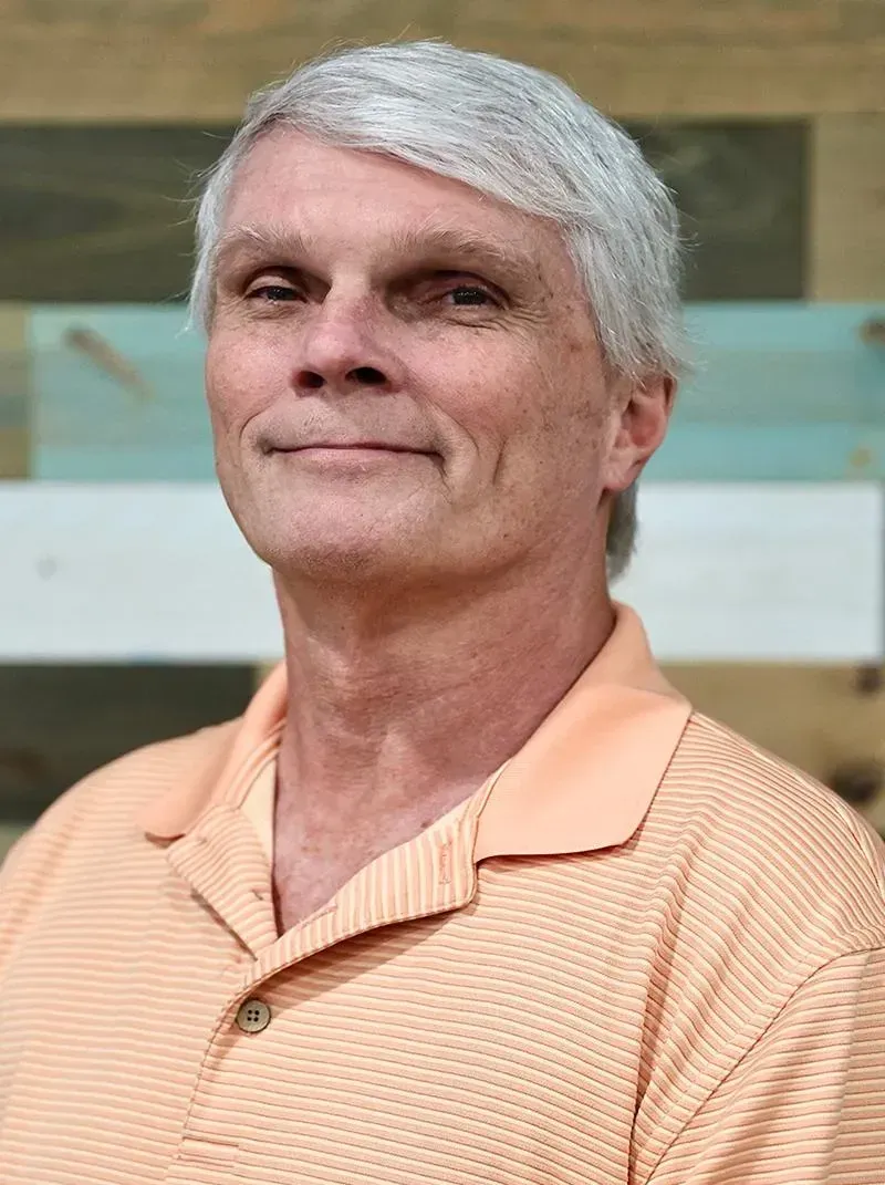 A man with gray hair is smiling for the camera