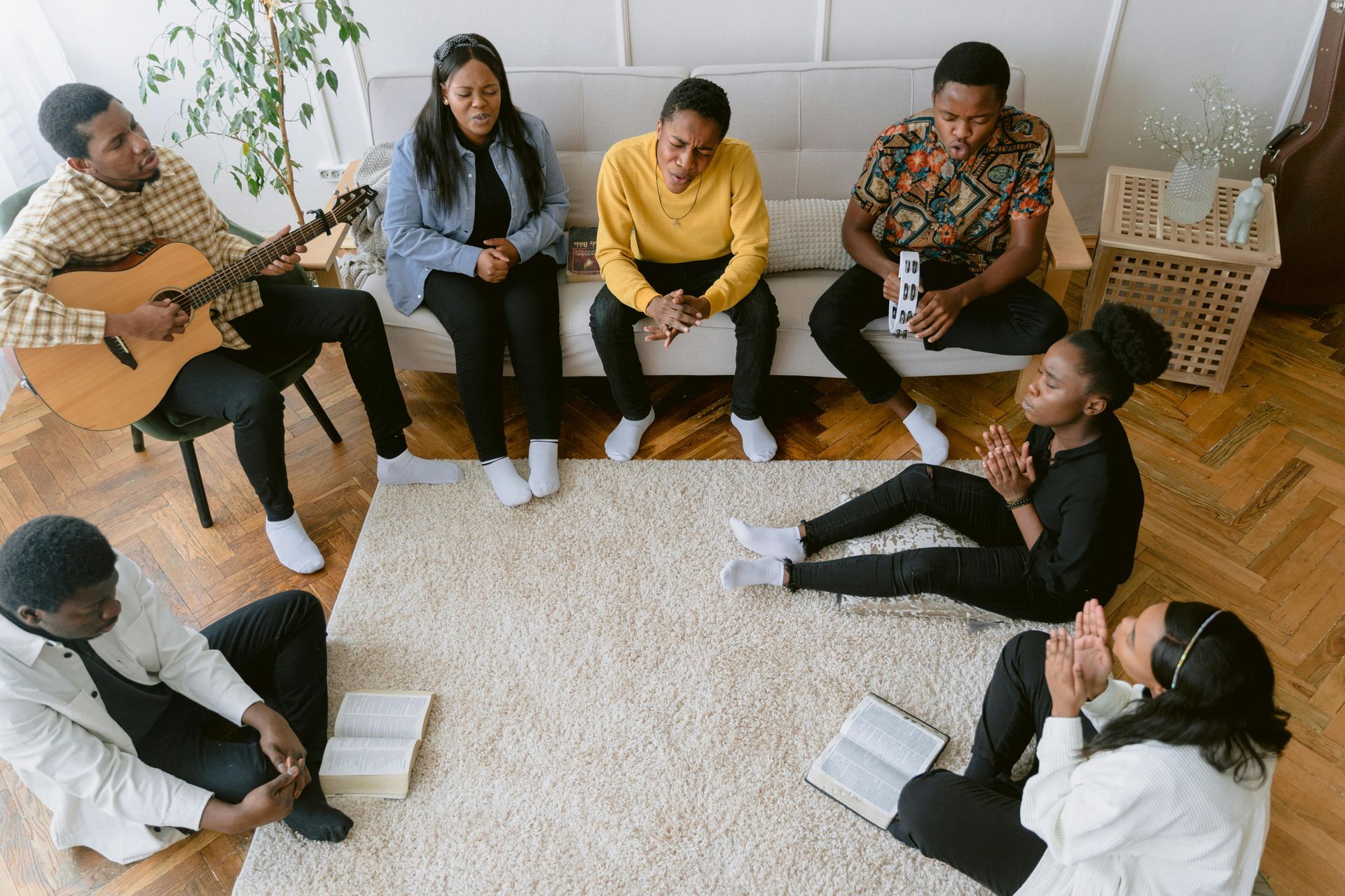 A group of people are sitting in a circle on the floor in a living room.
