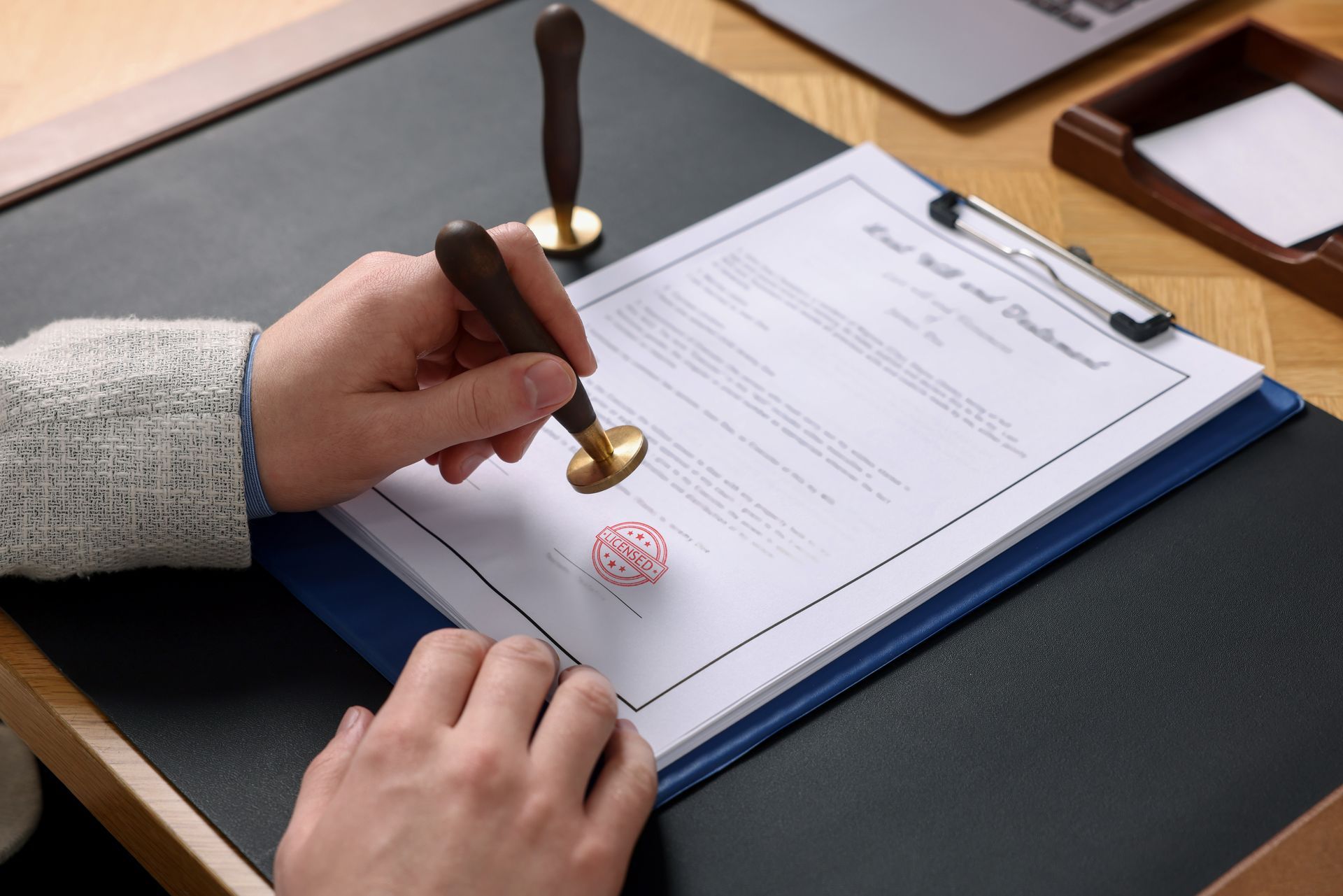 Person pressing a wax seal onto a document on a clipboard at a desk.