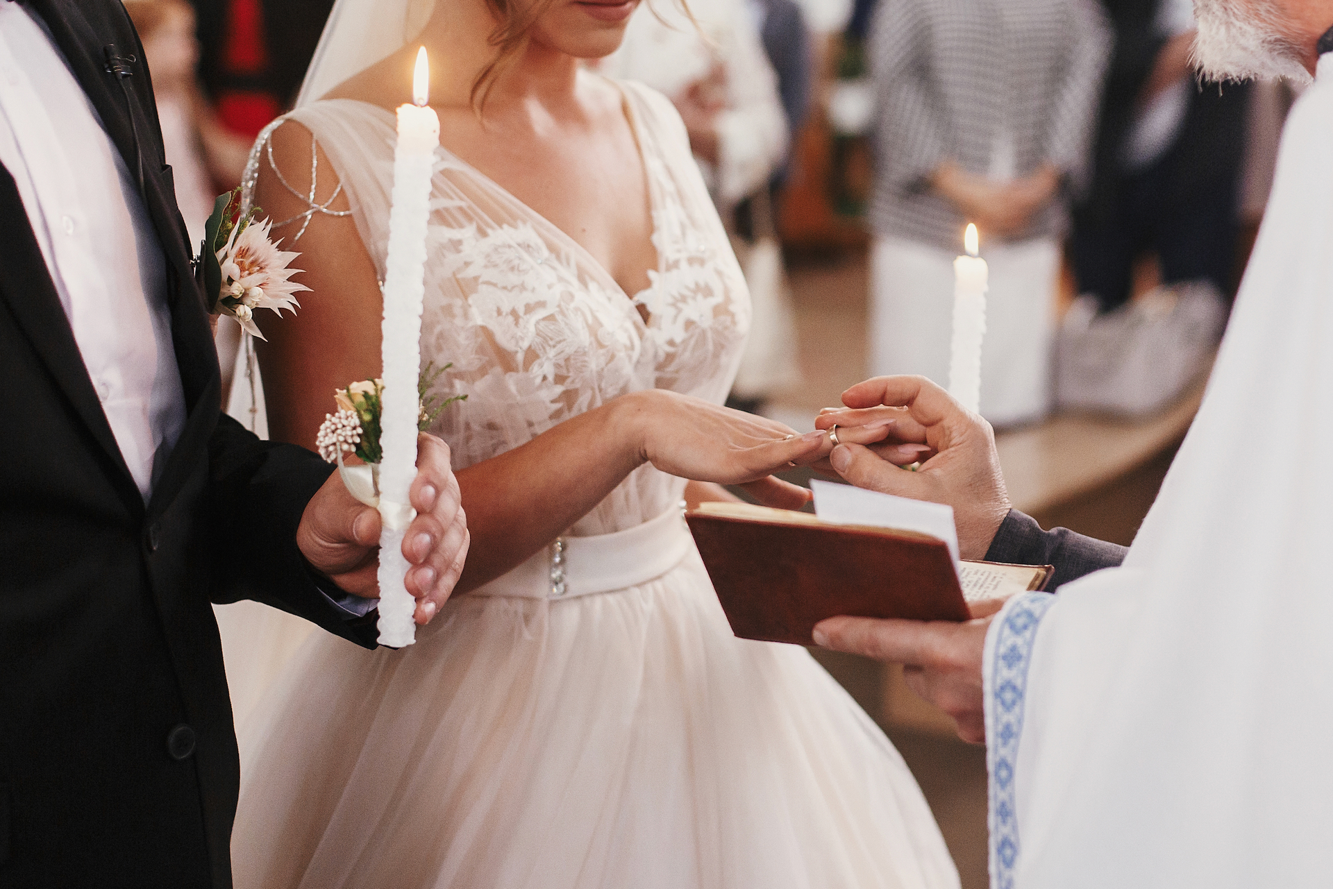 A bride and groom are holding candles during their wedding ceremony in a church.