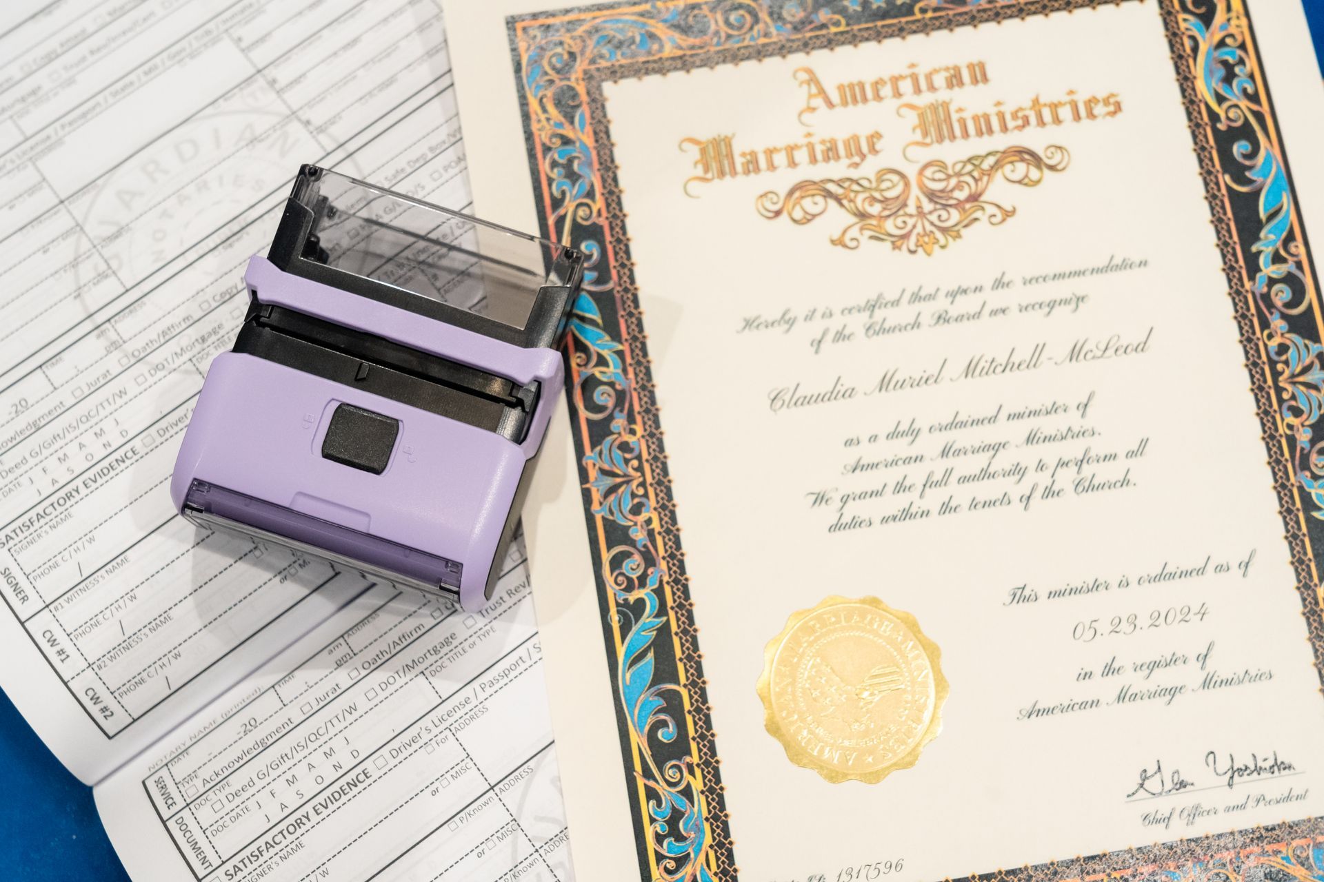 A purple stamp and a marriage certificate next to a document with form fields on a blue surface.