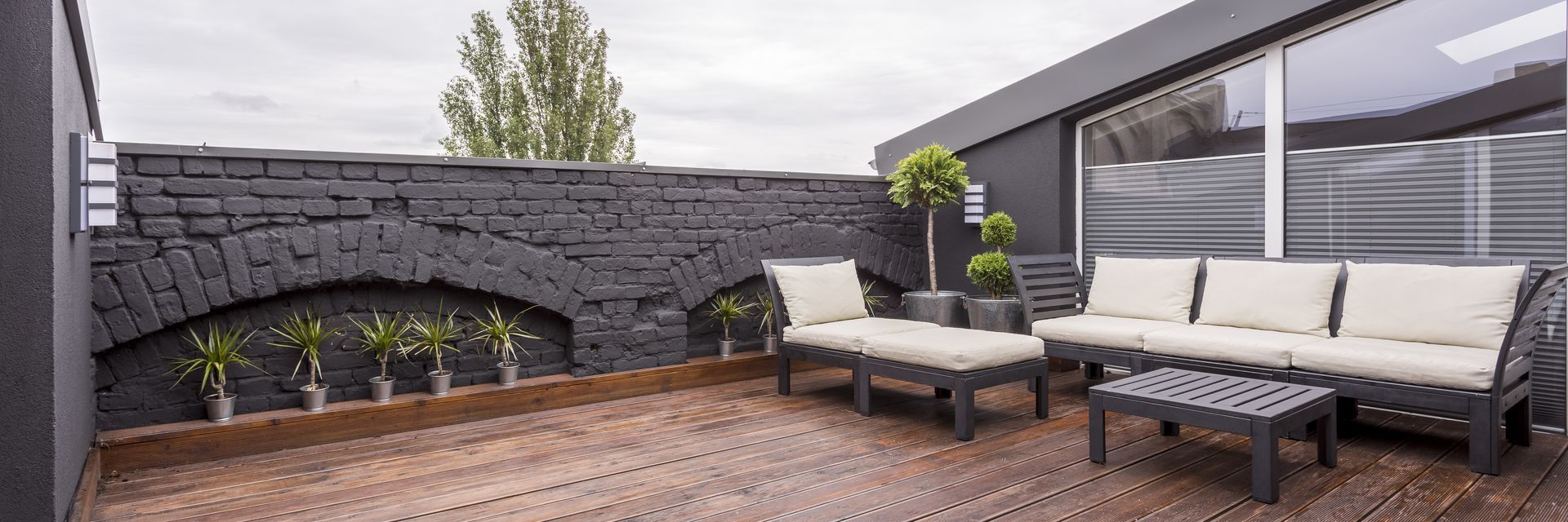 wood rooftop deck with grey brick side wall