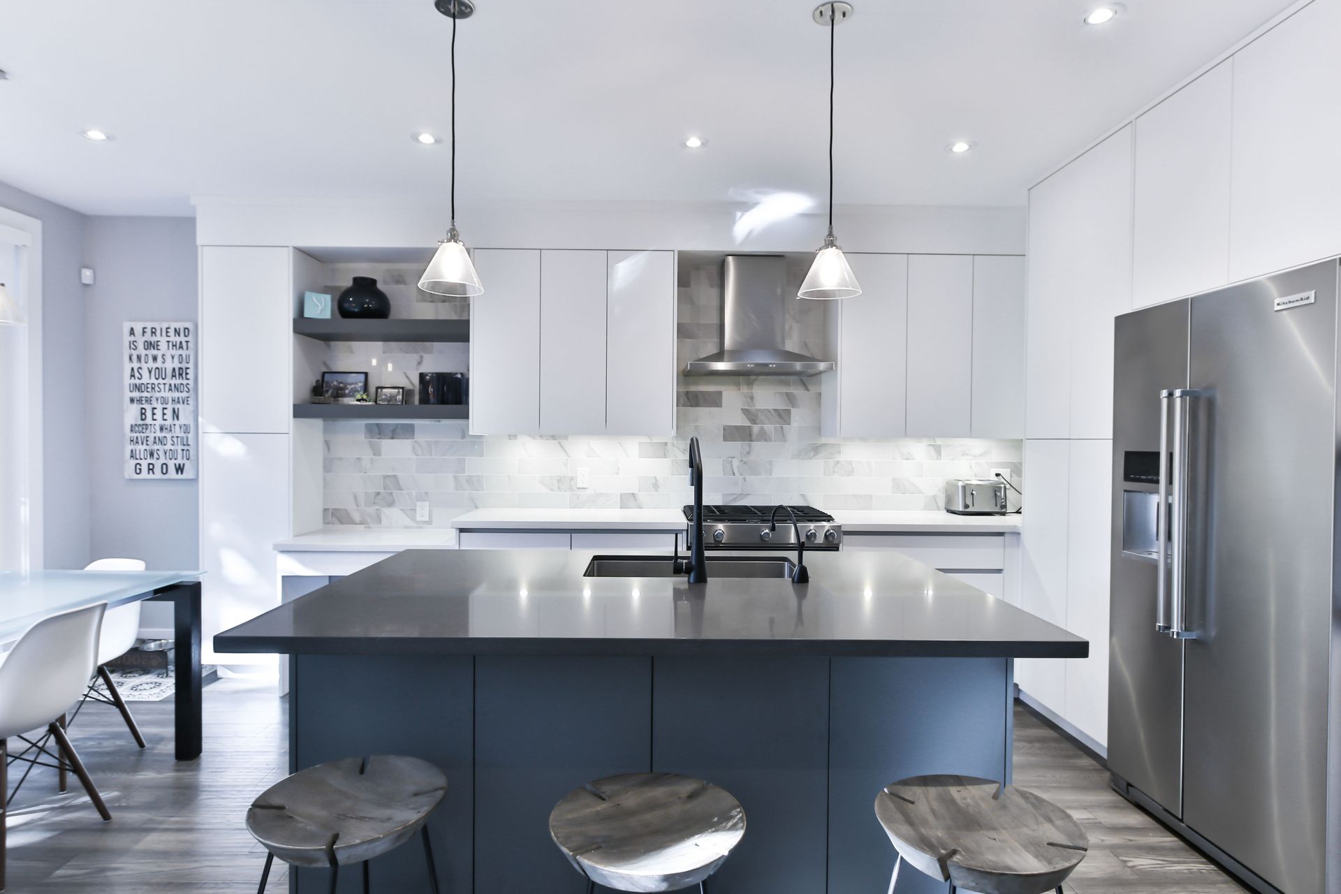 white kitchen cabinetry with black quartz counter over blue centre island