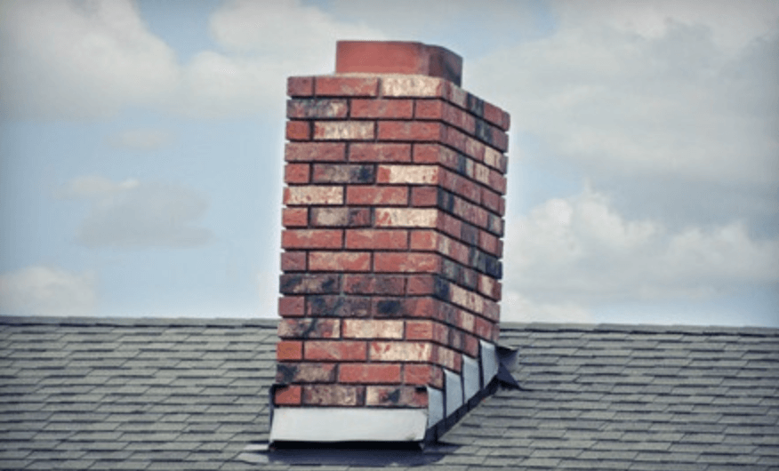 A brick chimney is sitting on top of a roof.