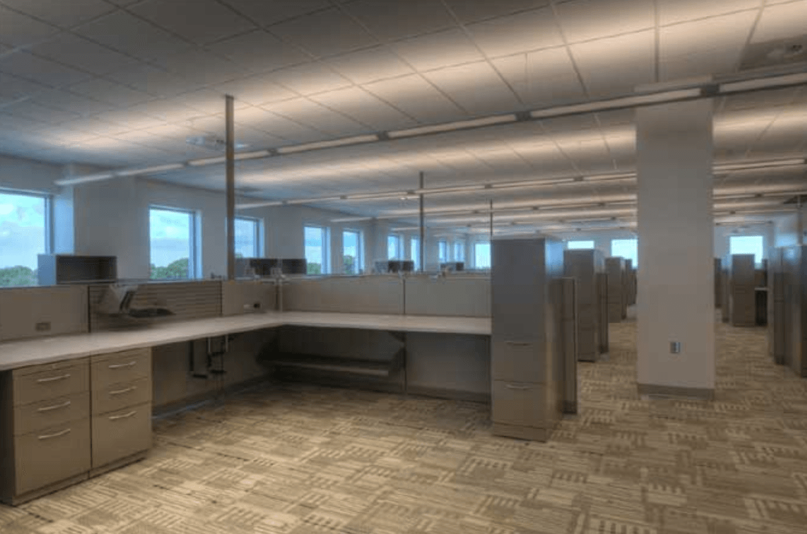 An empty office with cubicles and a lot of windows.