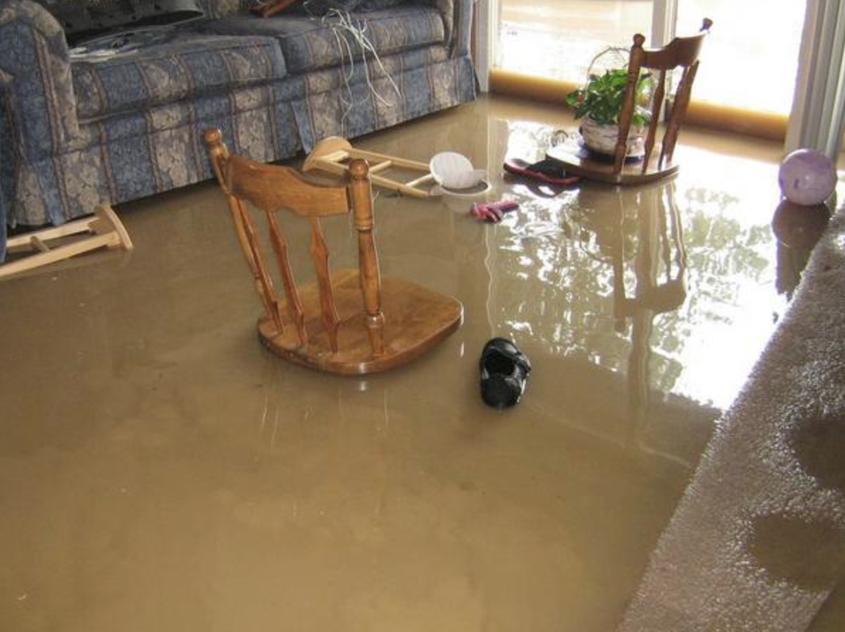 A flooded living room with a rocking chair and a couch.