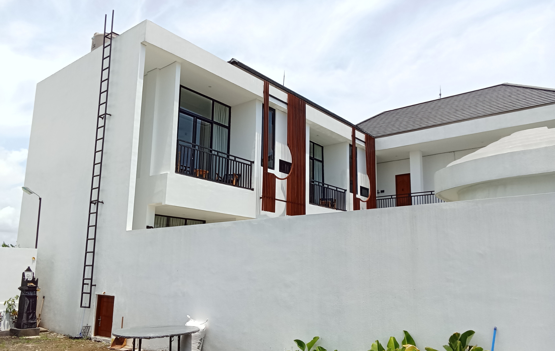 White building with balconies, brown accents, and a fire escape ladder.