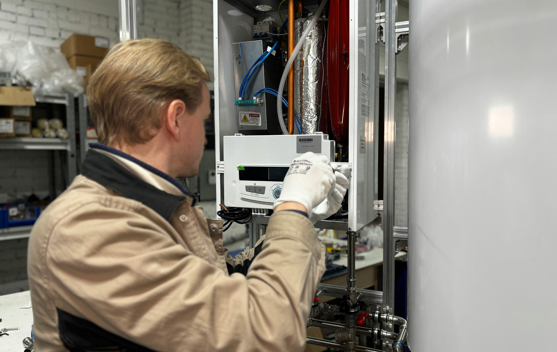 Technician in gloves working on a white heating unit, indoors.
