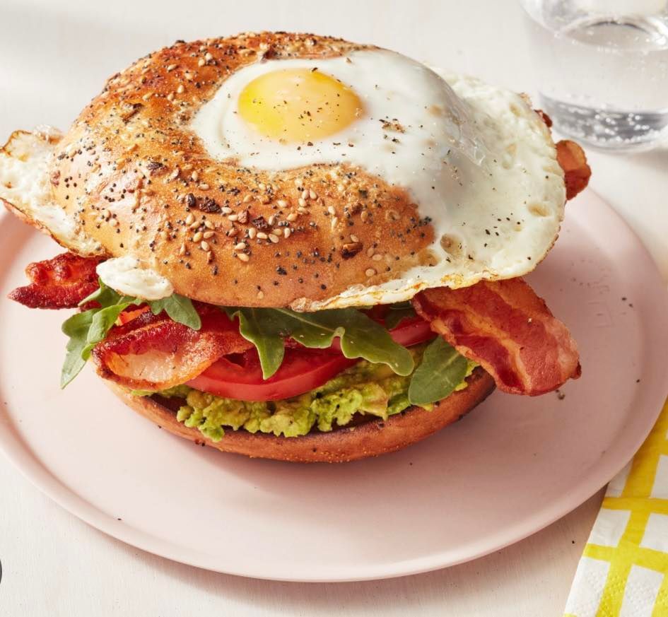A bagel sandwich with eggs bacon and lettuce on a plate
