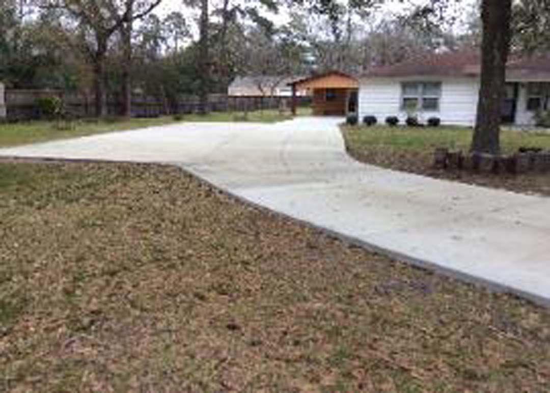 There is a concrete driveway leading to a house.
