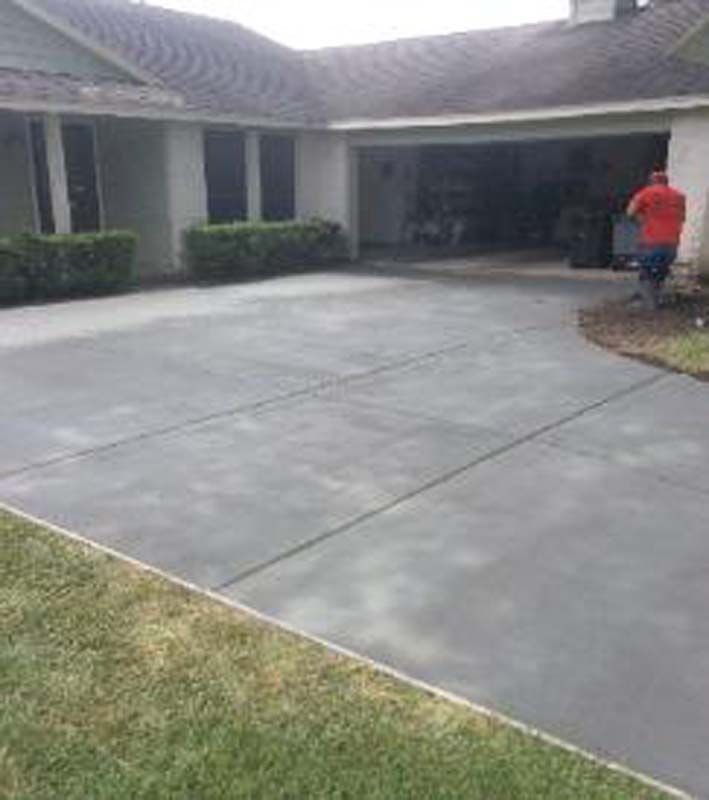 A man is standing in a driveway in front of a house.