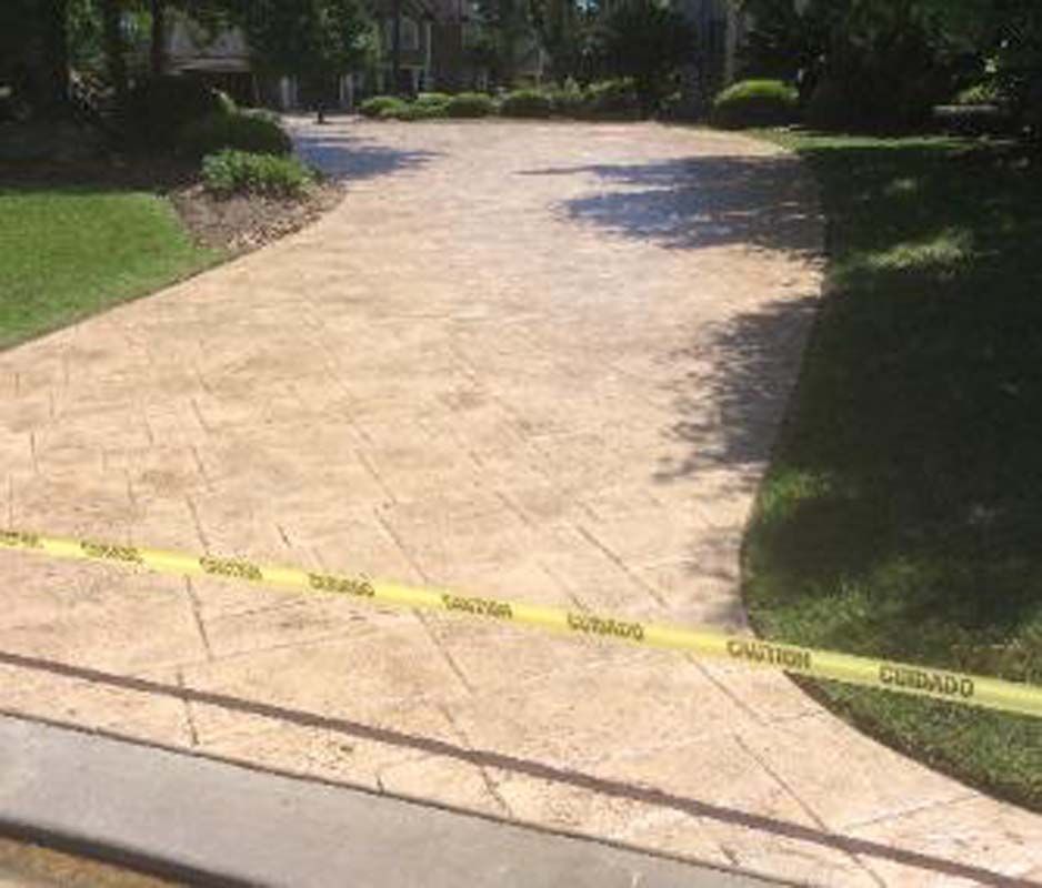 A concrete driveway with a yellow caution tape along the side of it.