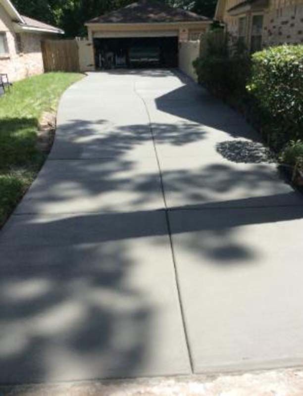 A concrete driveway leading to a house with a garage.