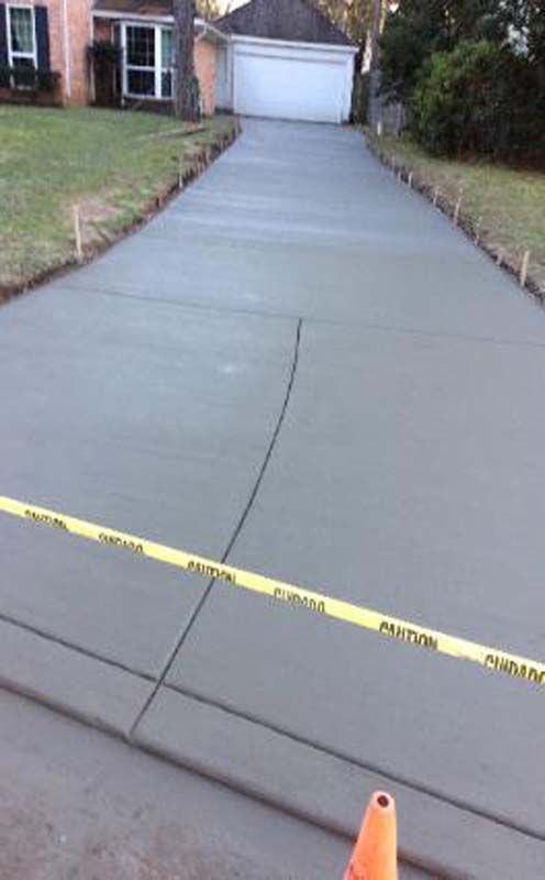 A concrete driveway is being built in front of a house.