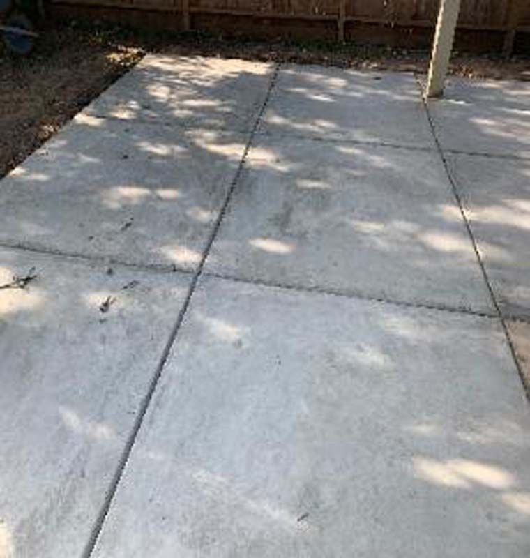 A concrete patio with a wooden fence in the background.