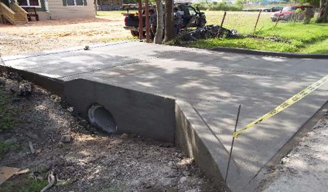 A concrete driveway is being built with a pipe in the middle of it.