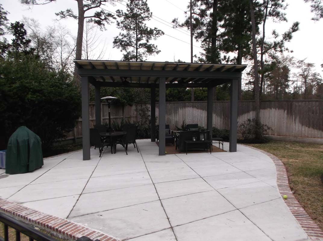 A patio with a pergola and a table and chairs