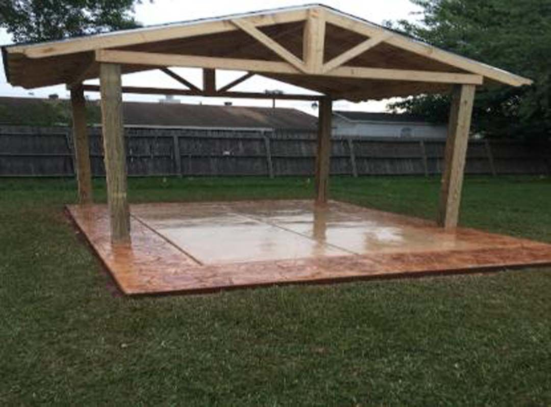 A wooden gazebo is sitting in the middle of a lush green field.