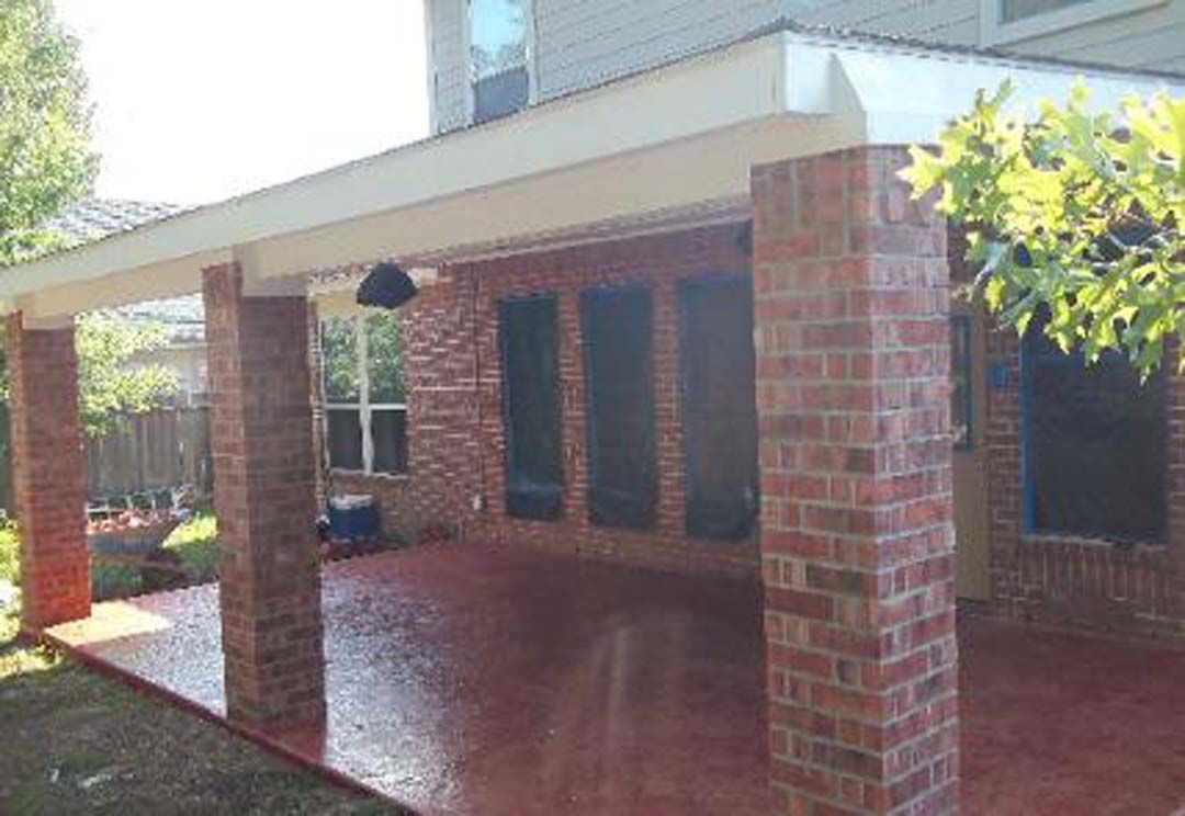 A brick house with a covered patio in front of it.