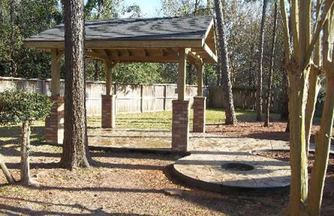 There is a pavilion in the middle of the woods surrounded by trees.
