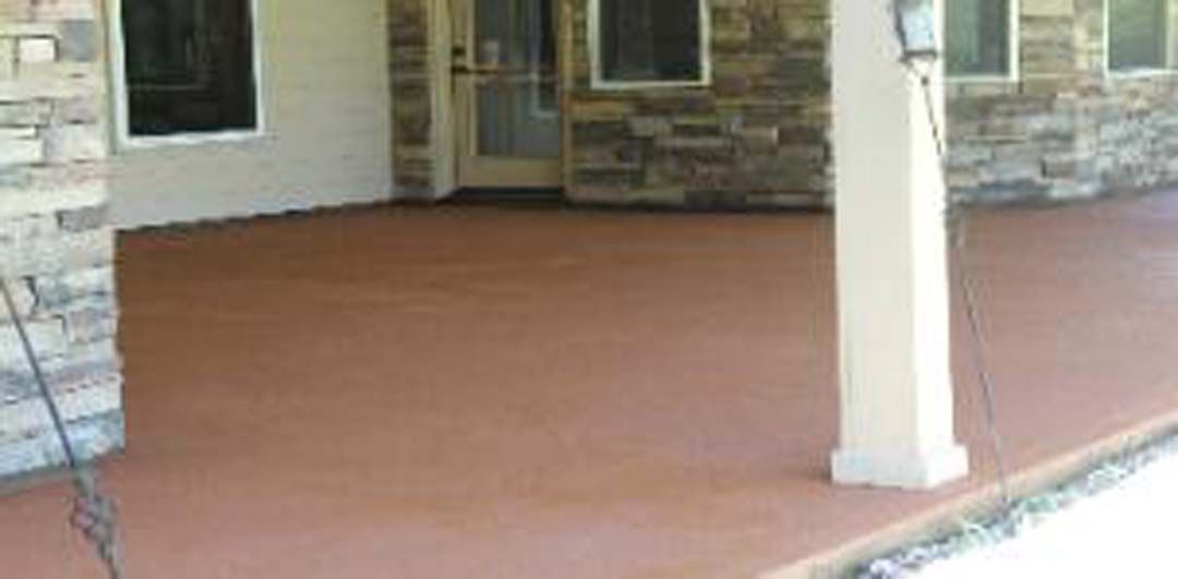 A porch with a concrete floor and a stone wall.