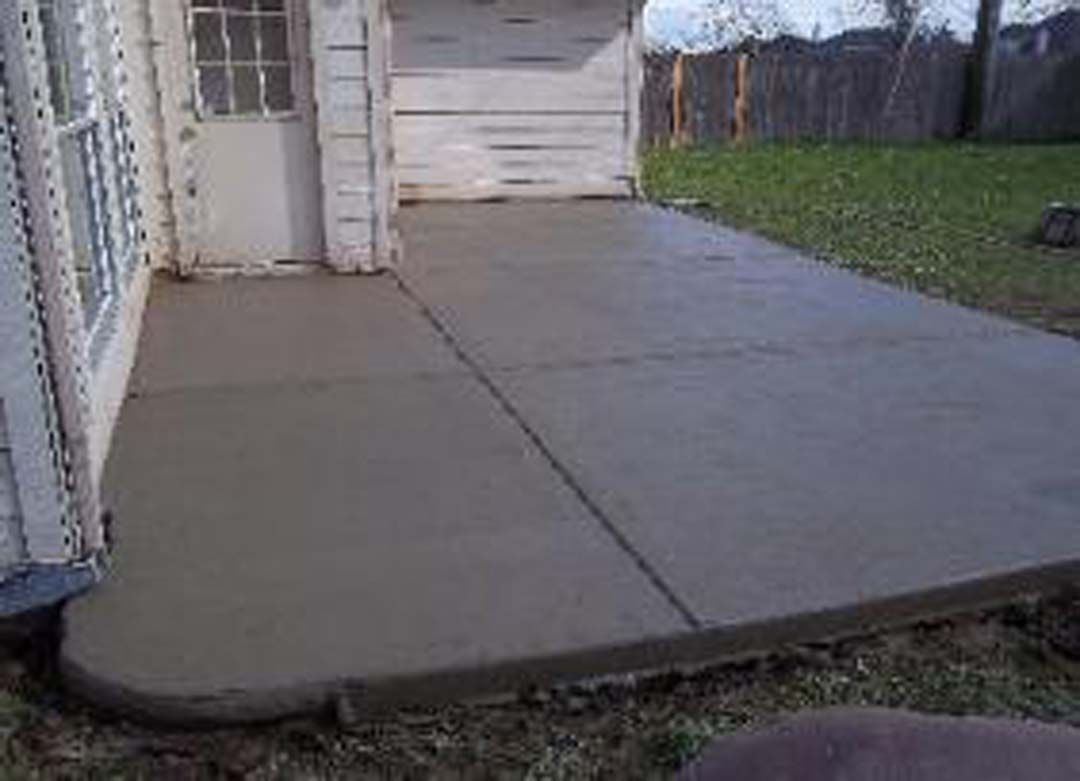 A concrete patio is being built in front of a garage door.