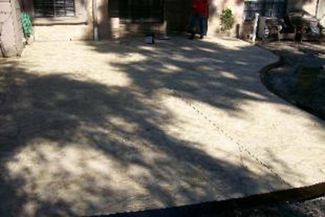 A man is standing on a concrete patio in front of a house.