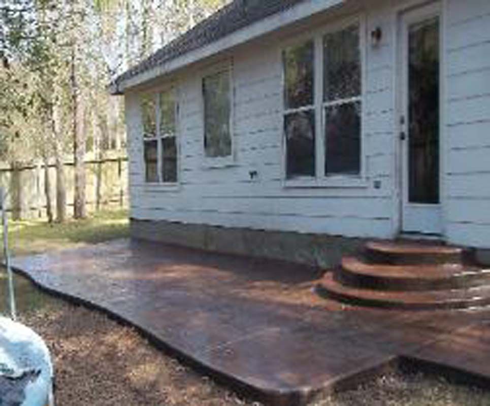 A white house with a concrete patio and stairs in front of it.