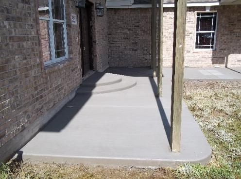 A brick house with a concrete walkway in front of it