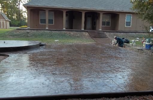 A man is working on a concrete driveway in front of a house.