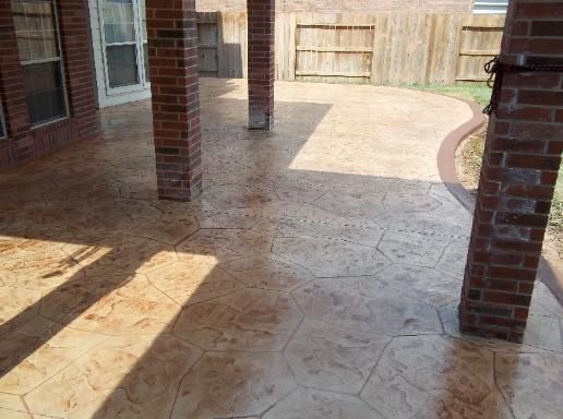 A patio with brick pillars and a fence in the background