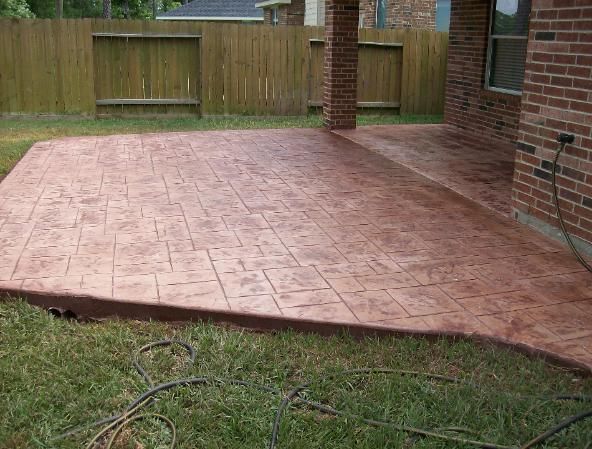 A brick house with a concrete patio in front of it.